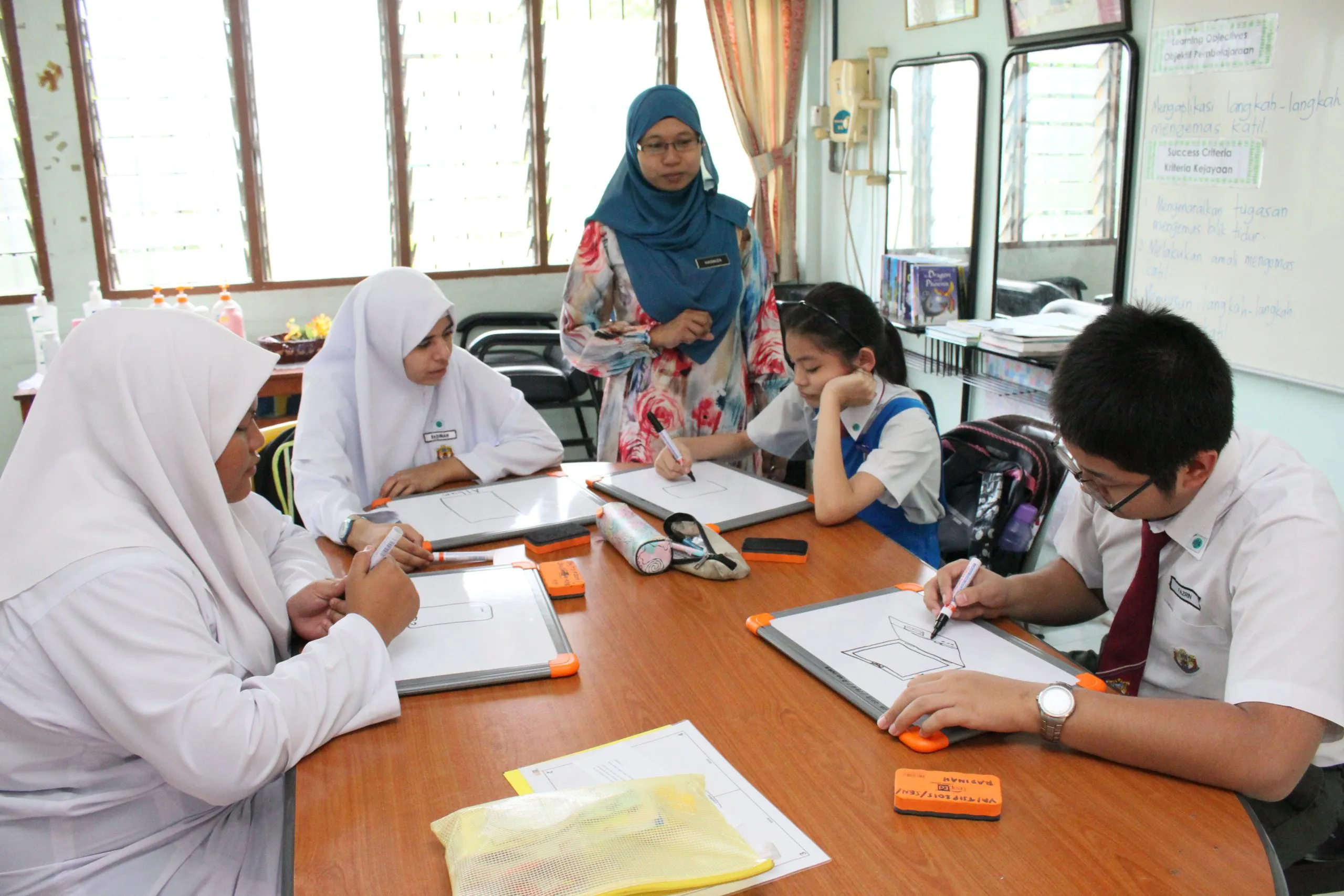 A teacher reviewing work with pupils at a table