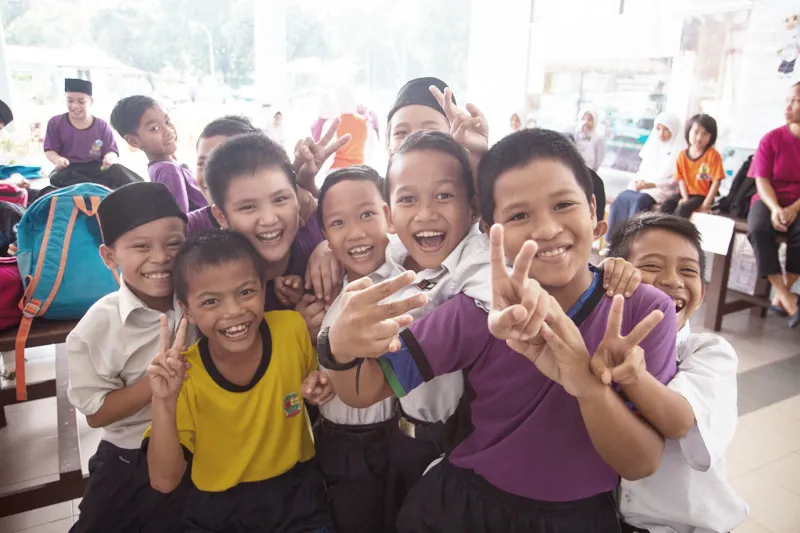 Smiling primary school pupils making peace signs