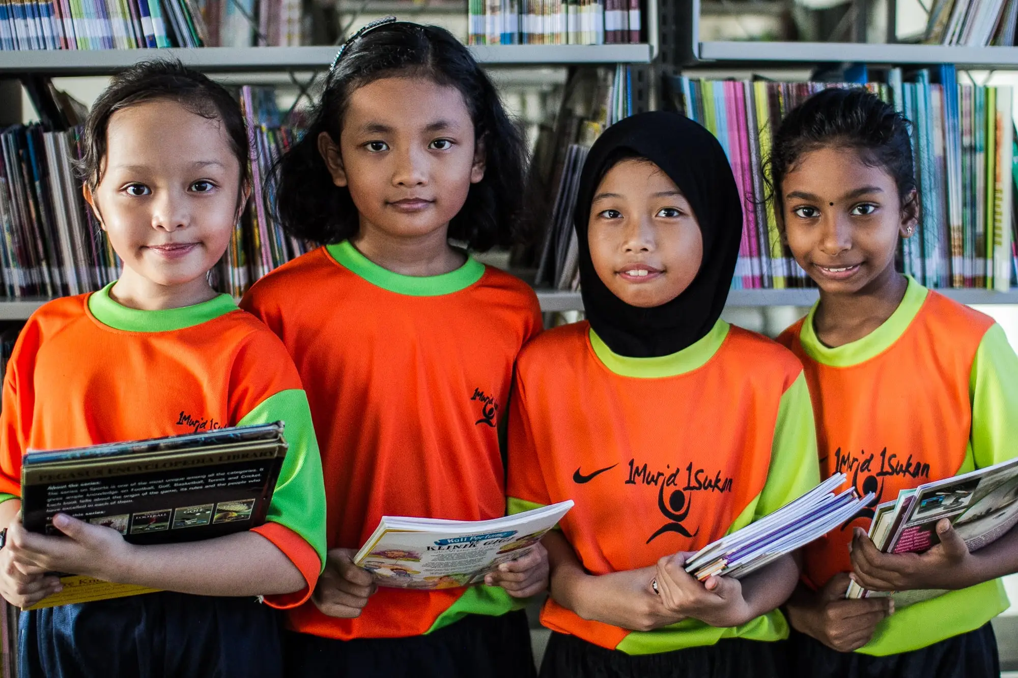 Four primary school girls in a library holding their reading books
